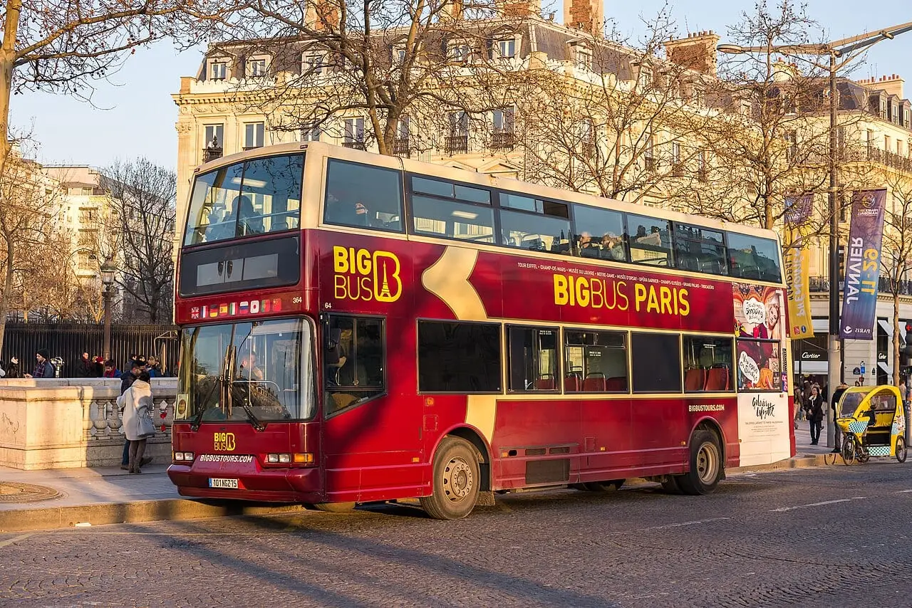 An open-top tour bus on a Paris boulevard