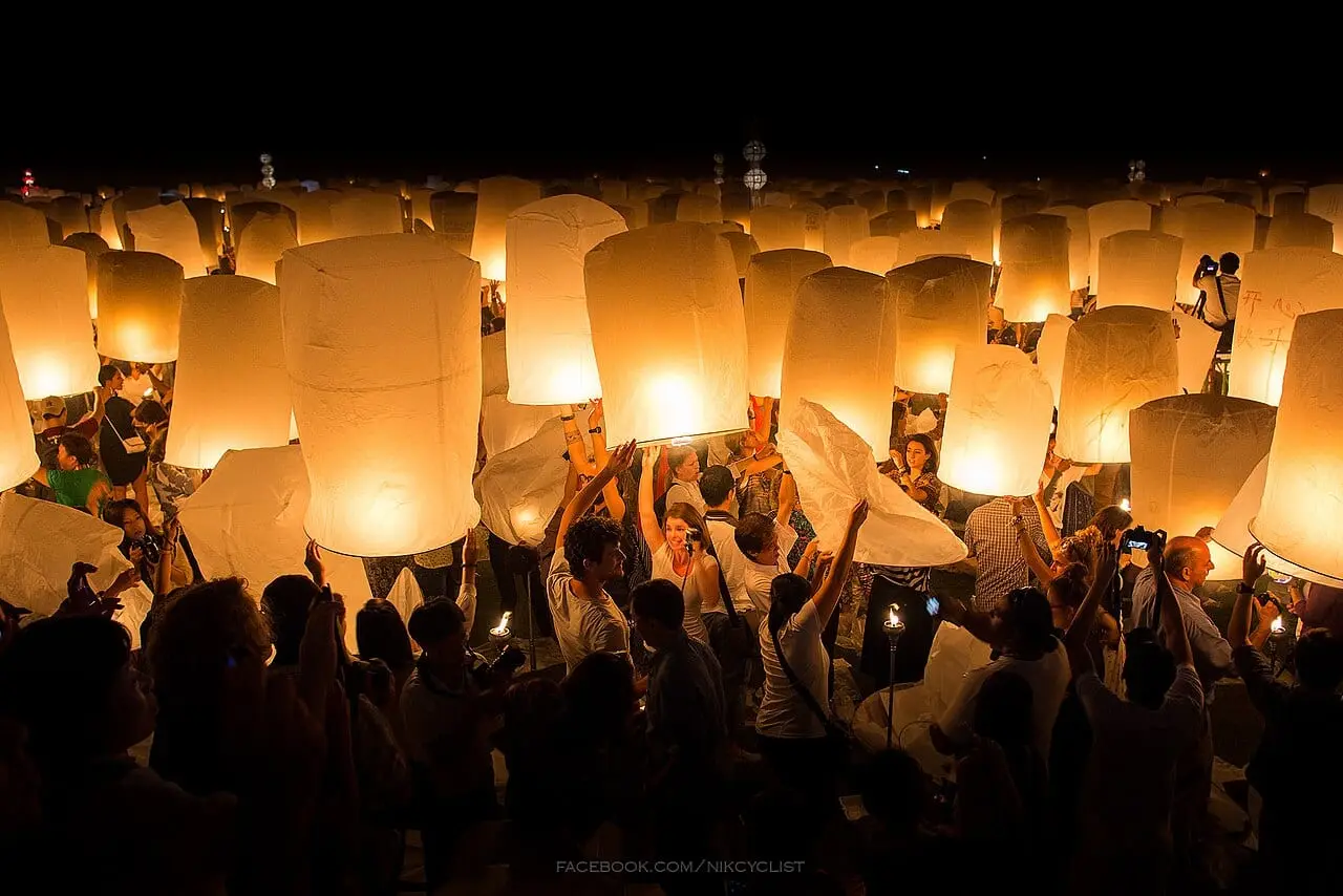 Thousands of sky lanterns rising over the crowd at Yi Peng, Chiang Mai