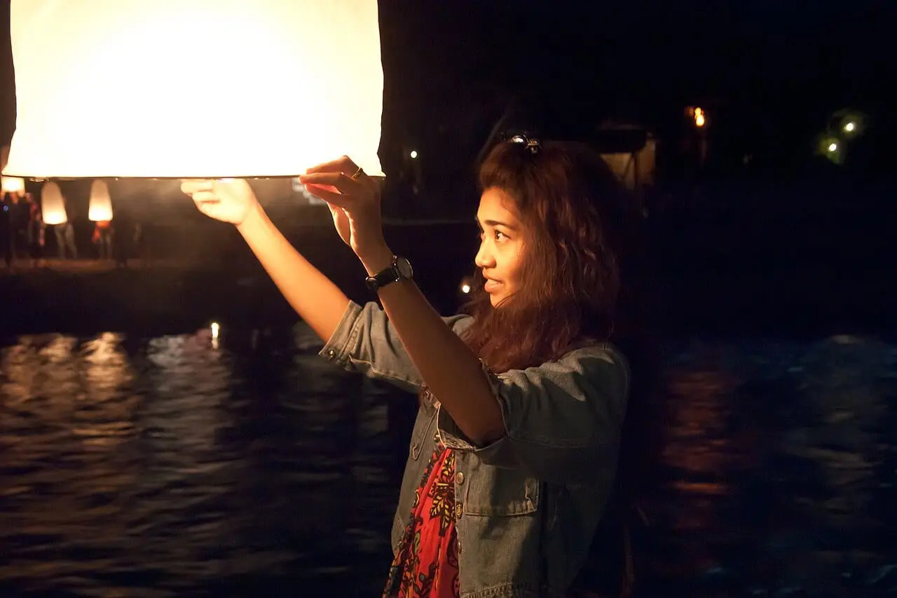 A woman releasing a lantern by the water