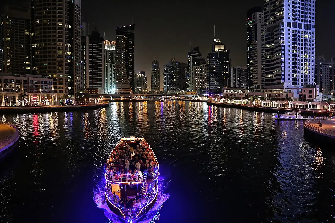 A lit-up cruise boat on Dubai Marina at night