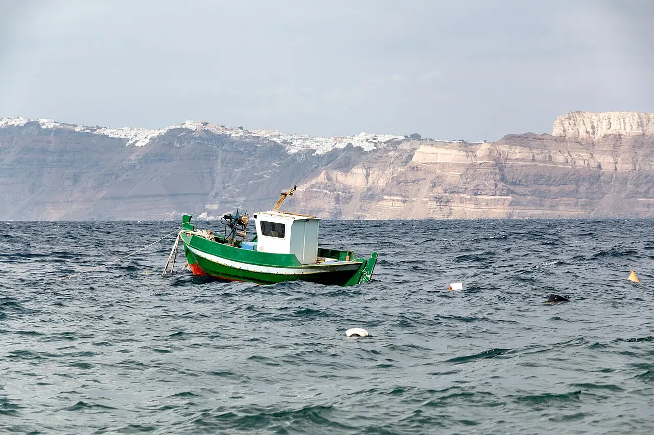 A boat below Santorini's cliffs