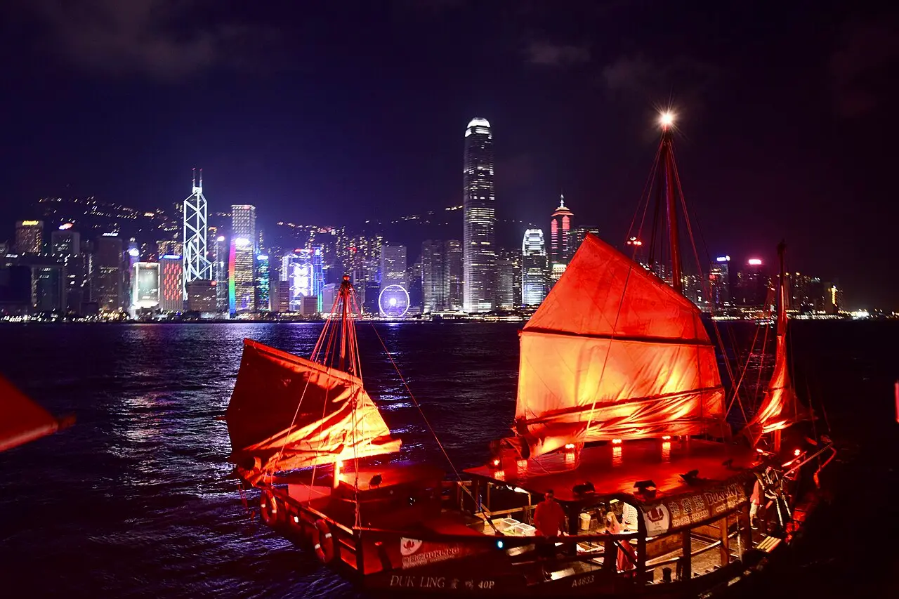 The Aqua Luna junk lit up red on Victoria Harbour at night