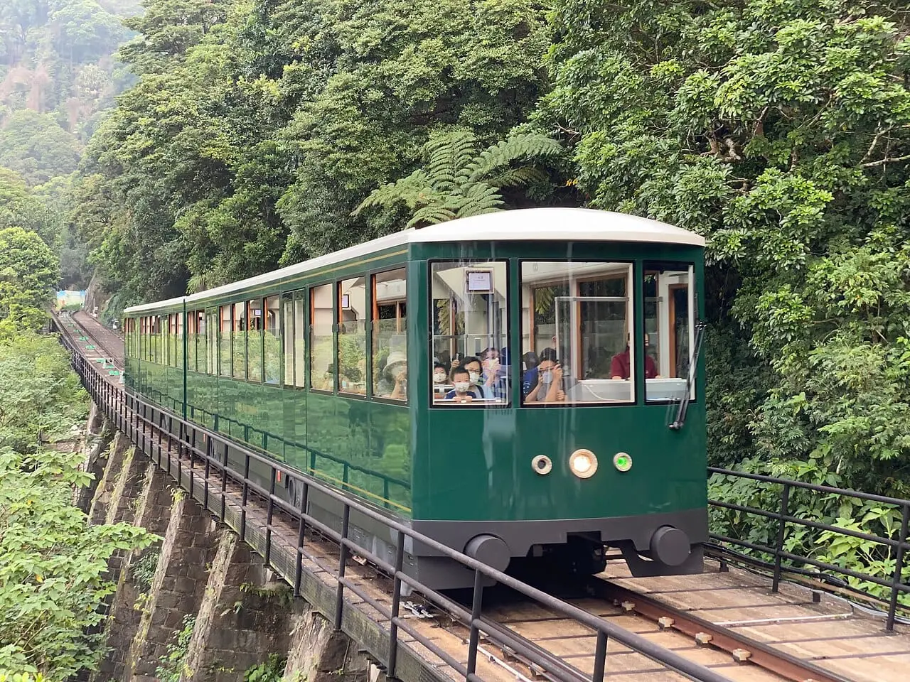The green Peak Tram climbing the steep track to Victoria Peak