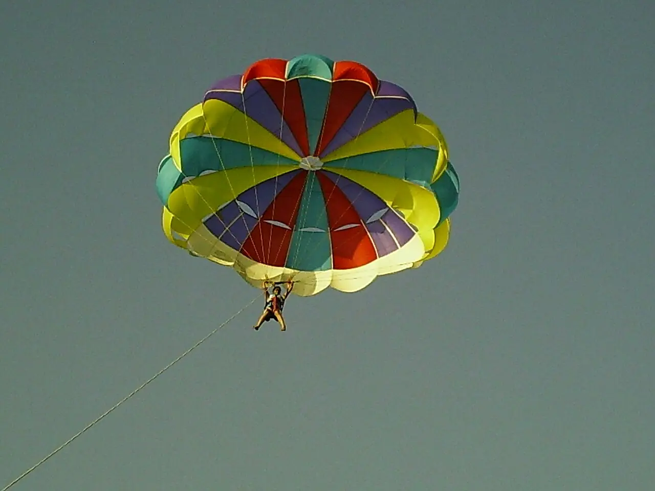 A colourful parasail high over the sea