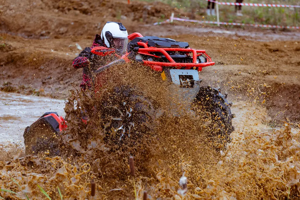 An ATV splashing through mud