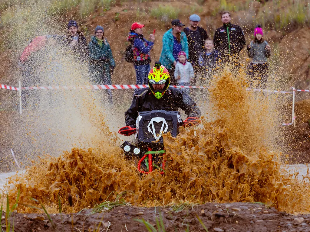 A rider powering an ATV through a muddy trail