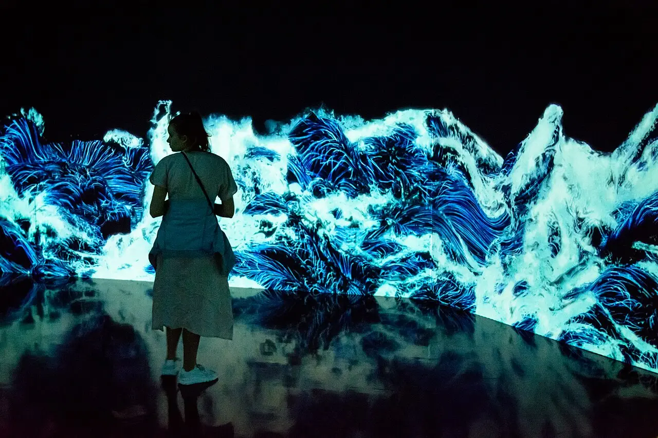 A visitor in front of a projected wave artwork