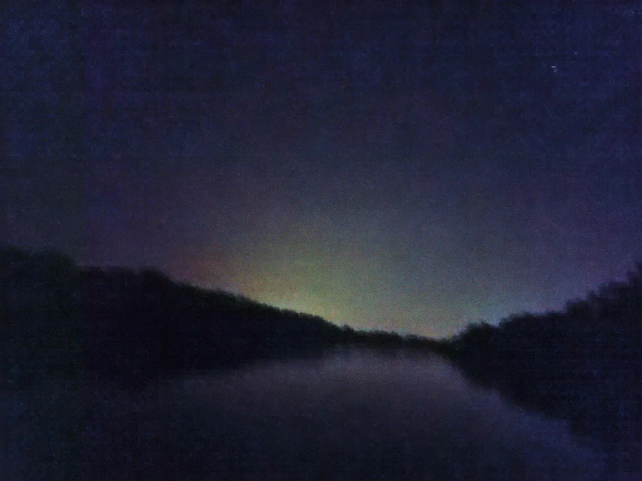 Fireflies glowing over the river at night