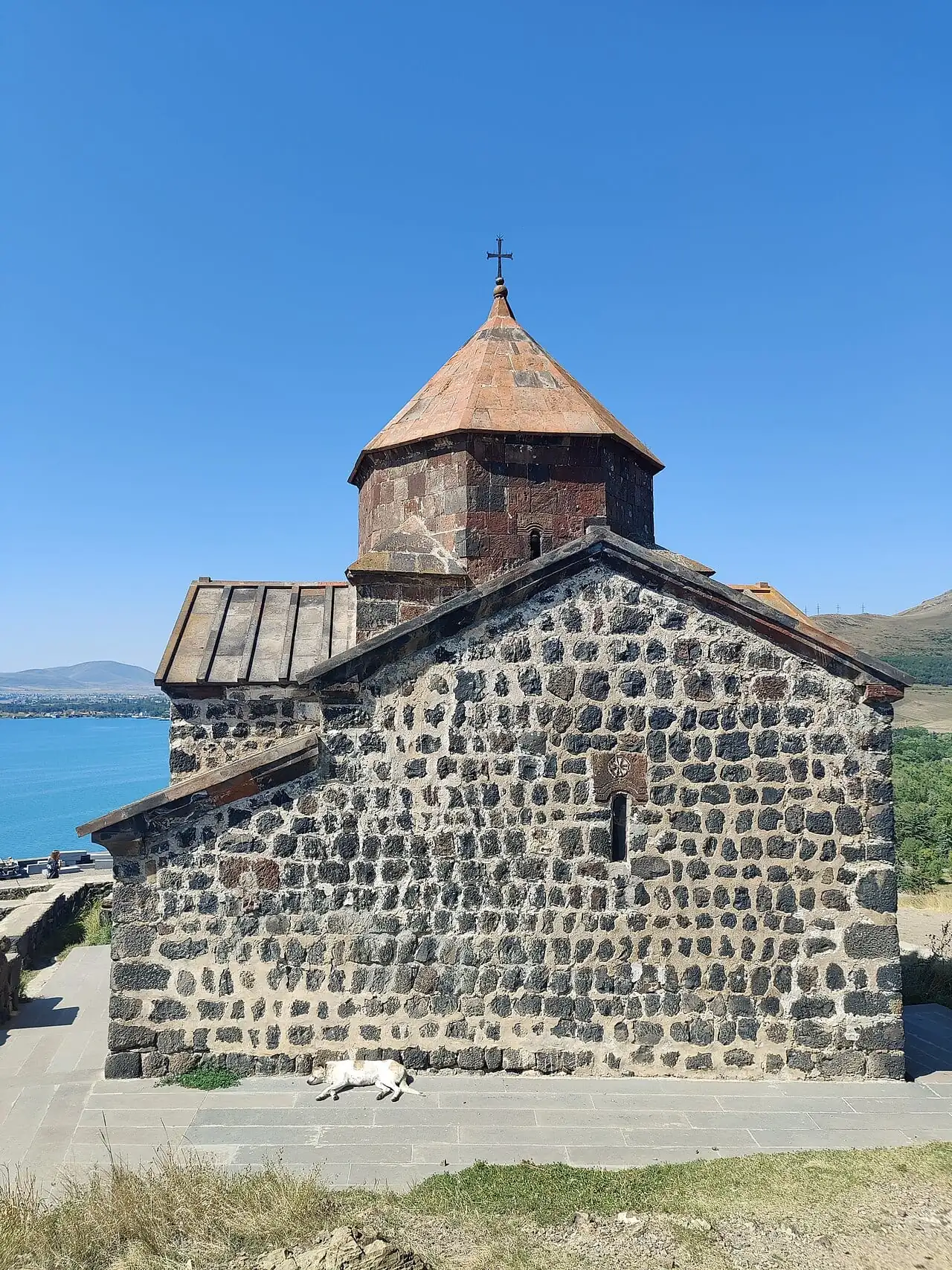 A stone church of Sevanavank with the lake behind