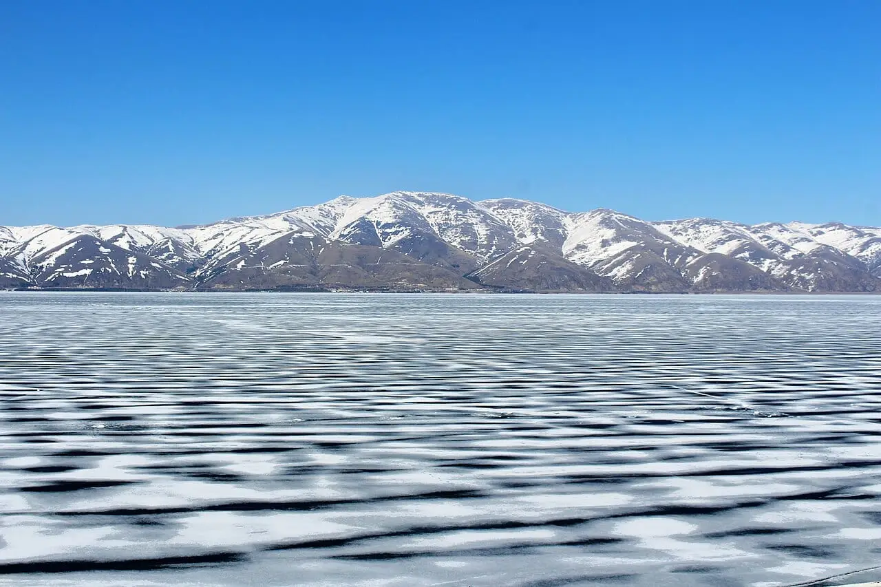 Lake Sevan frozen in winter, with snowy mountains