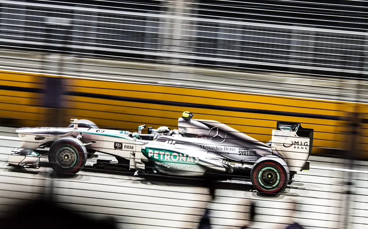 An F1 car speeding past the barriers at night