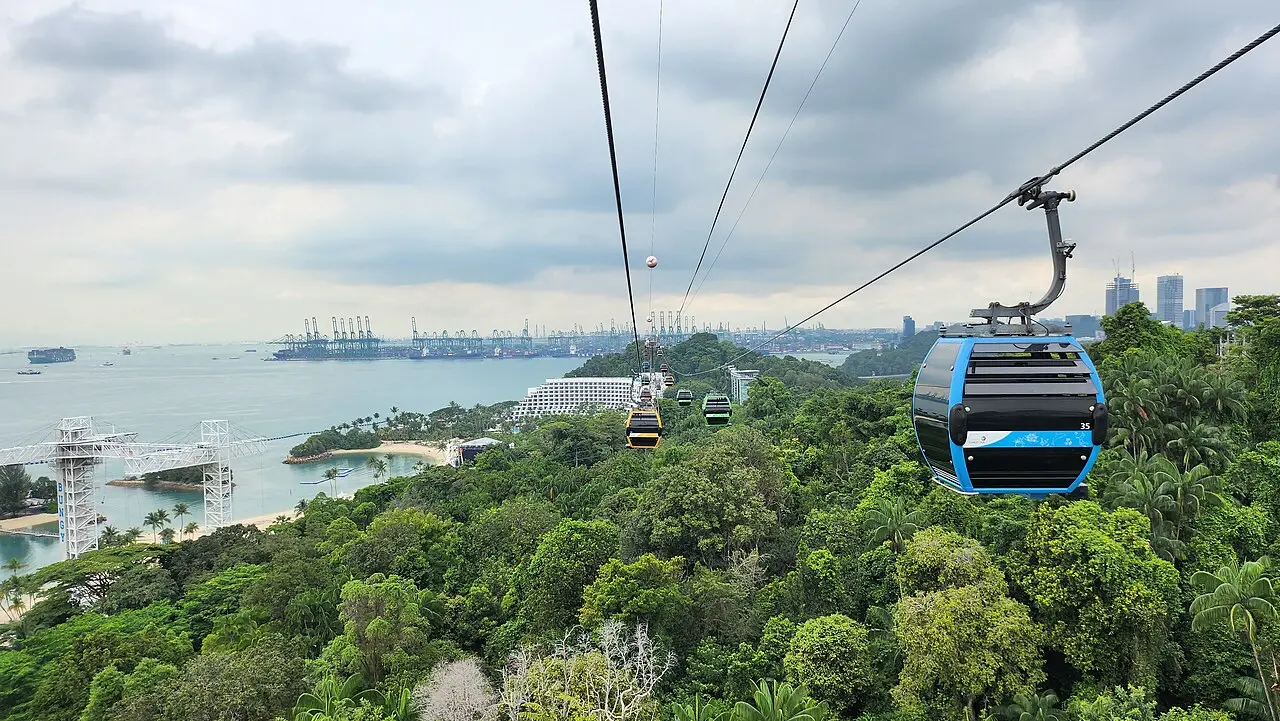 A cable car gliding over the rainforest of Sentosa towards the sea