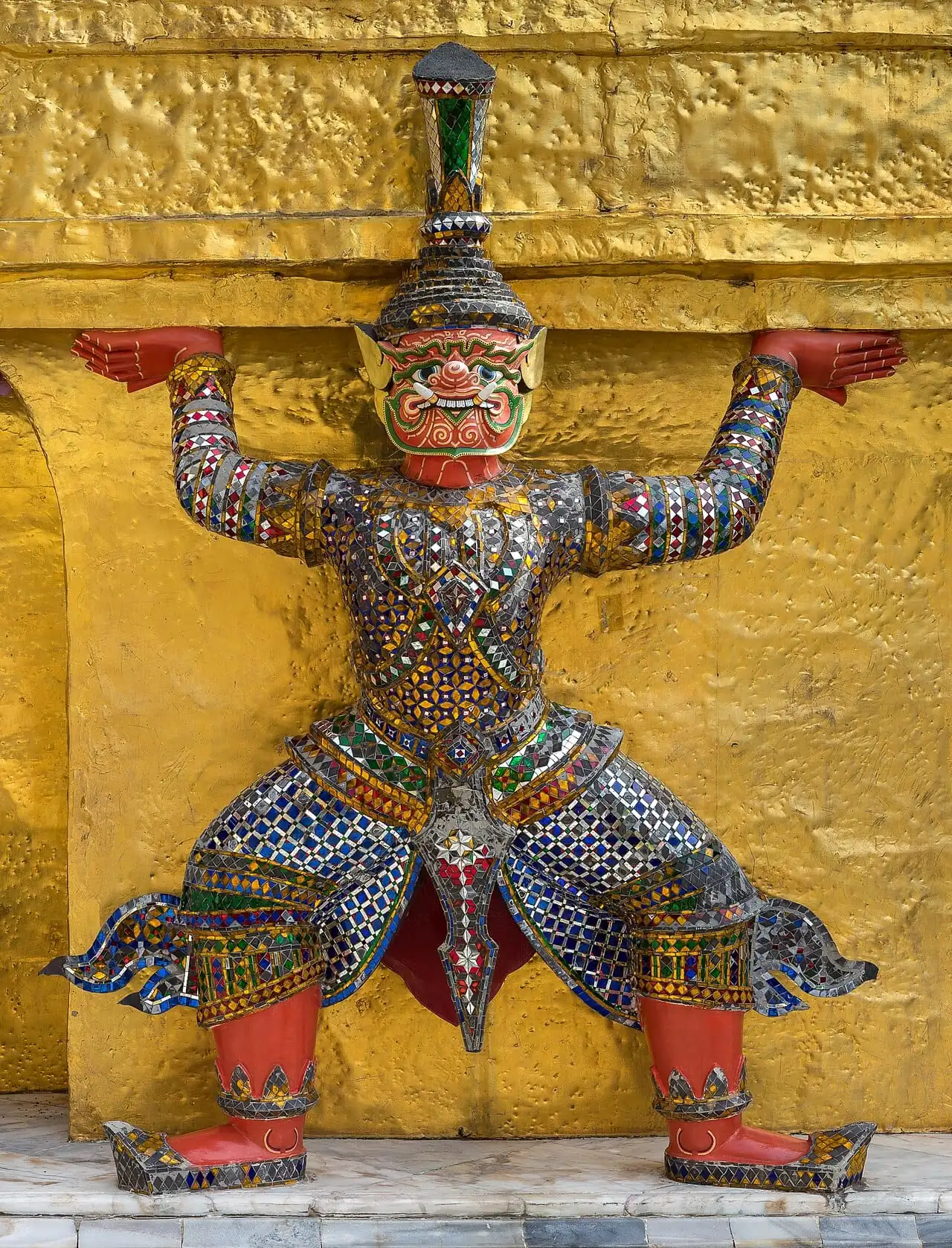 A demon guardian statue supporting a golden chedi at Wat Phra Kaew