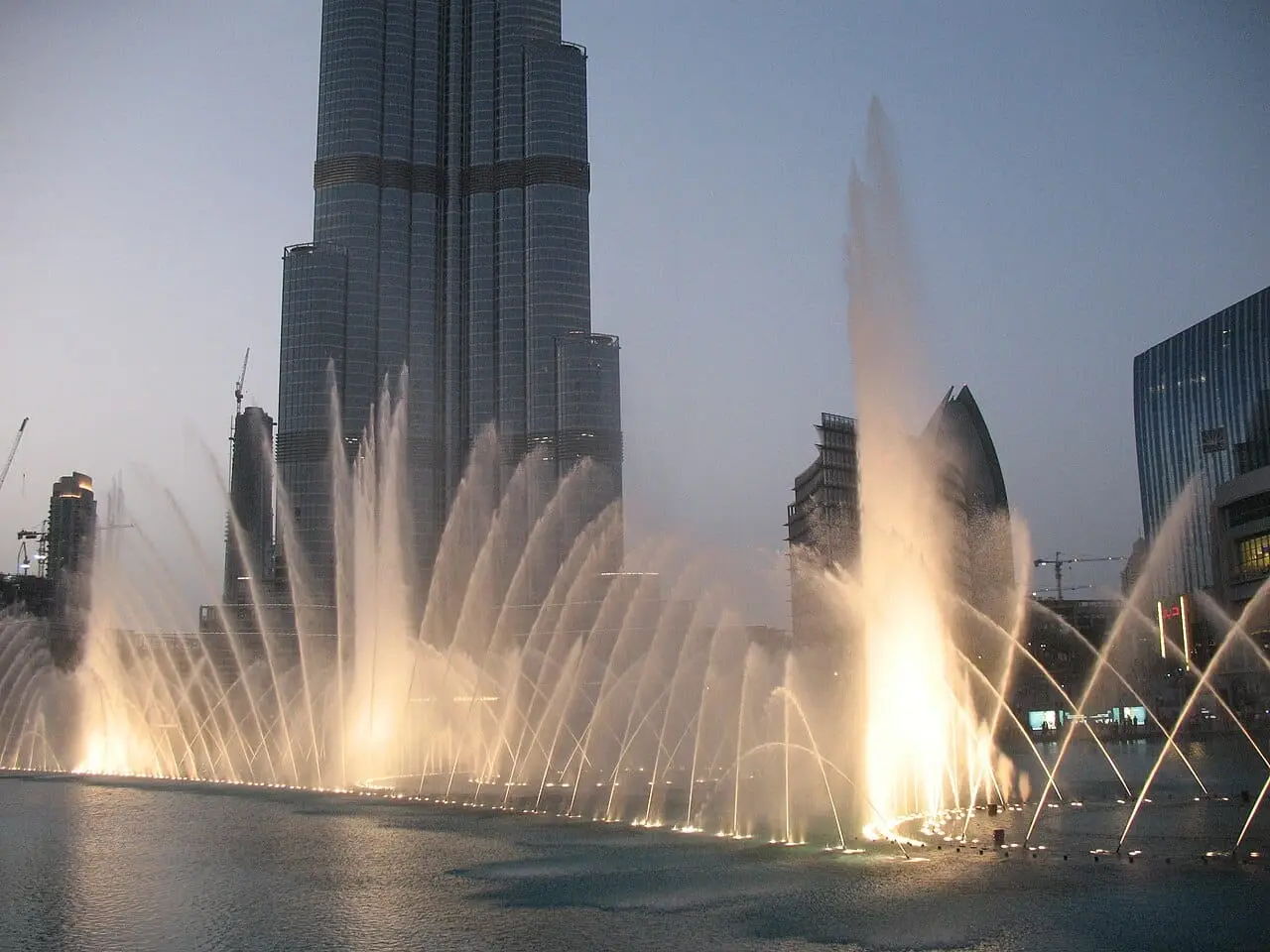 The Dubai Fountain in front of Downtown's towers at dusk