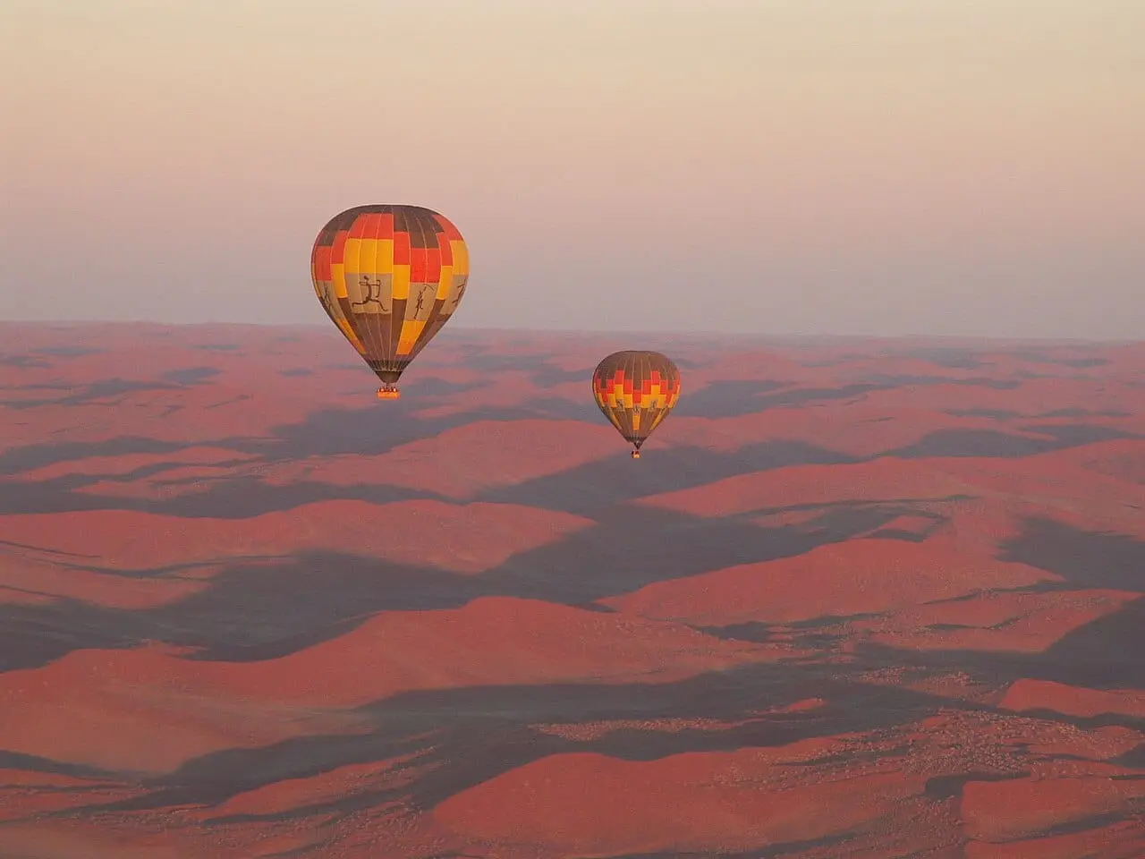 Hot air balloons over the dunes at sunrise