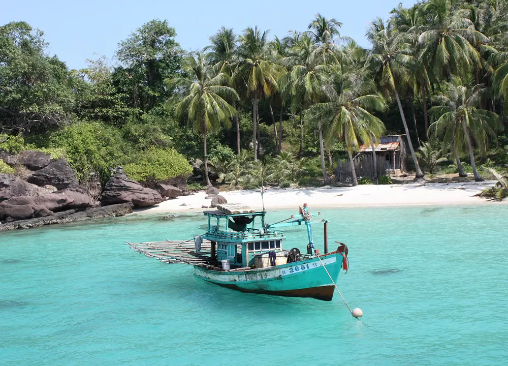 A boat moored in turquoise water off a palm-fringed beach near Phu Quoc