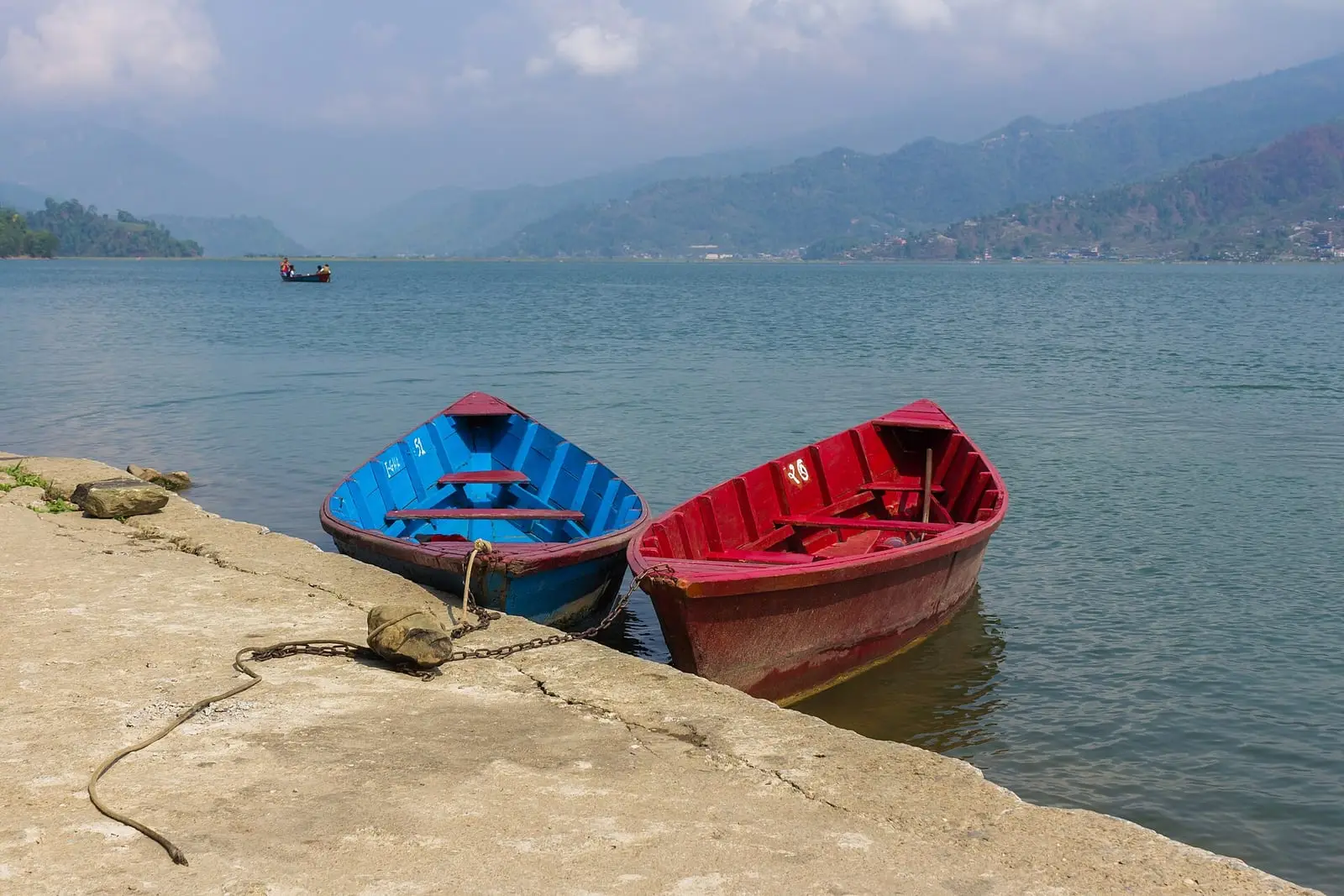 Red and blue rowing boats on the shore of Phewa Lake