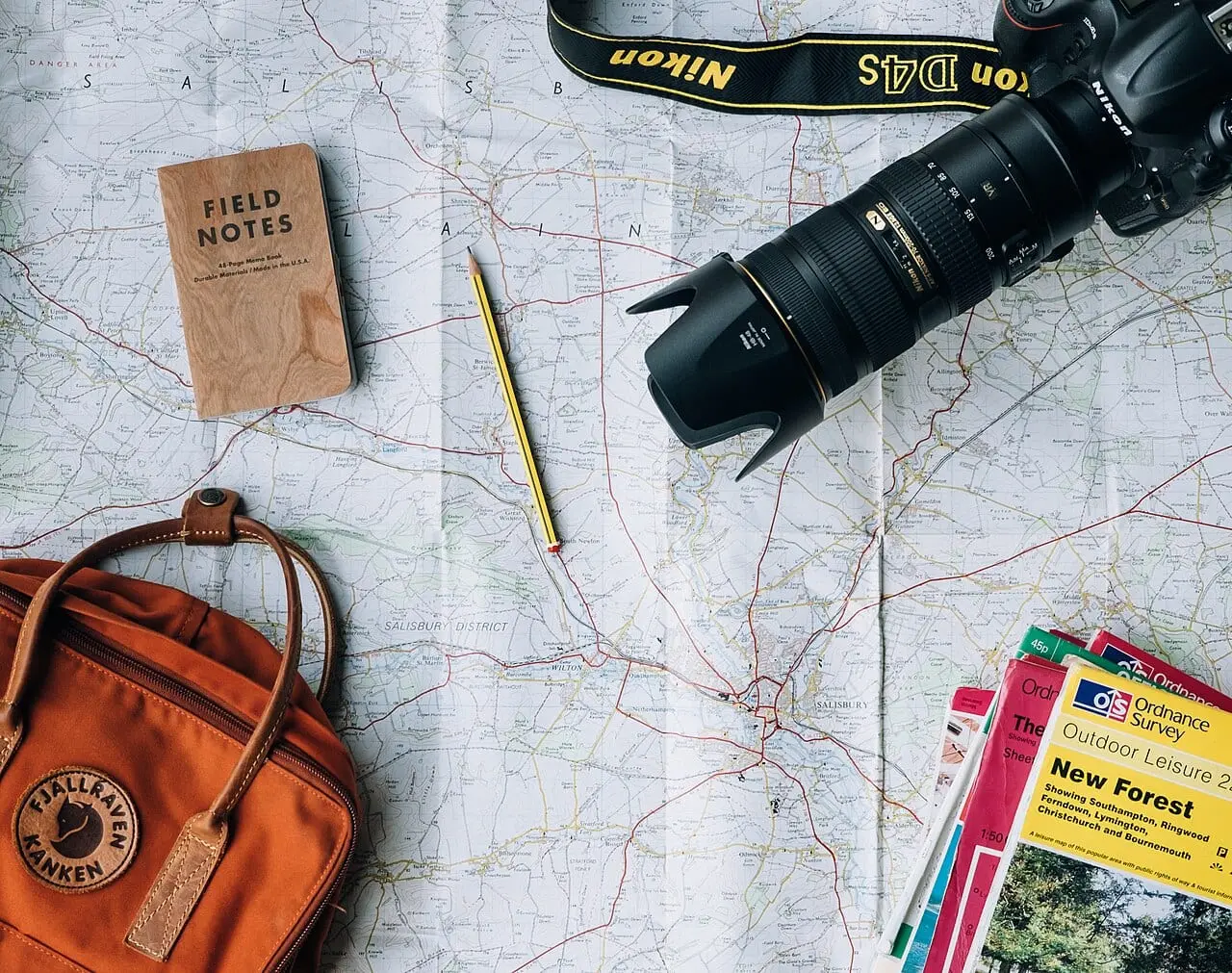 A map, notebook and camera laid out for planning a trip