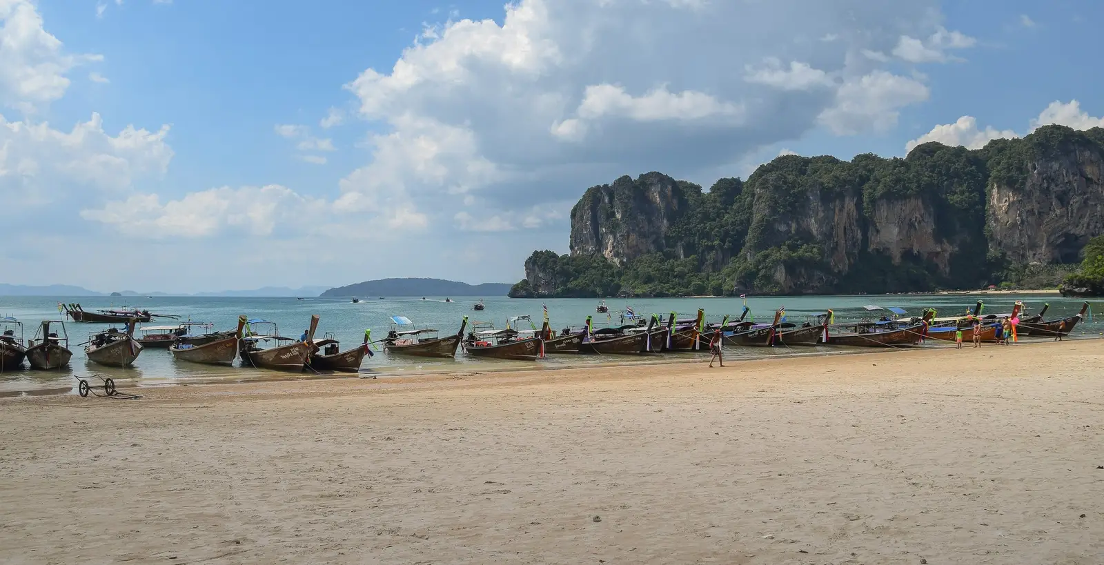 Longtail boats on a beach below limestone cliffs, Krabi
